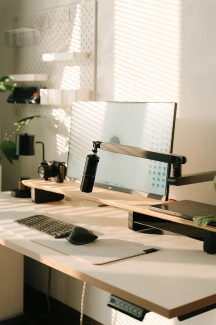 Vue en plongée d’un bureau de travail élégant avec deux écrans, un clavier, une souris et des accessoires modernes.